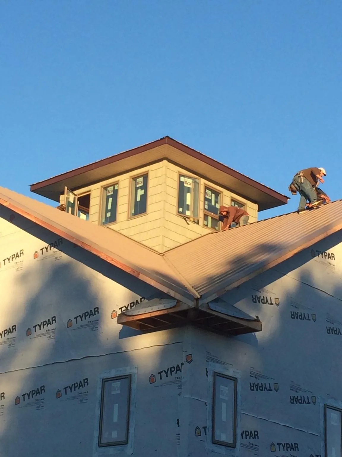 Roofers working around a rooftop cupola on a new metal roof at sunset — Roof Waterproofing in Lehigh by Roofing Brothers